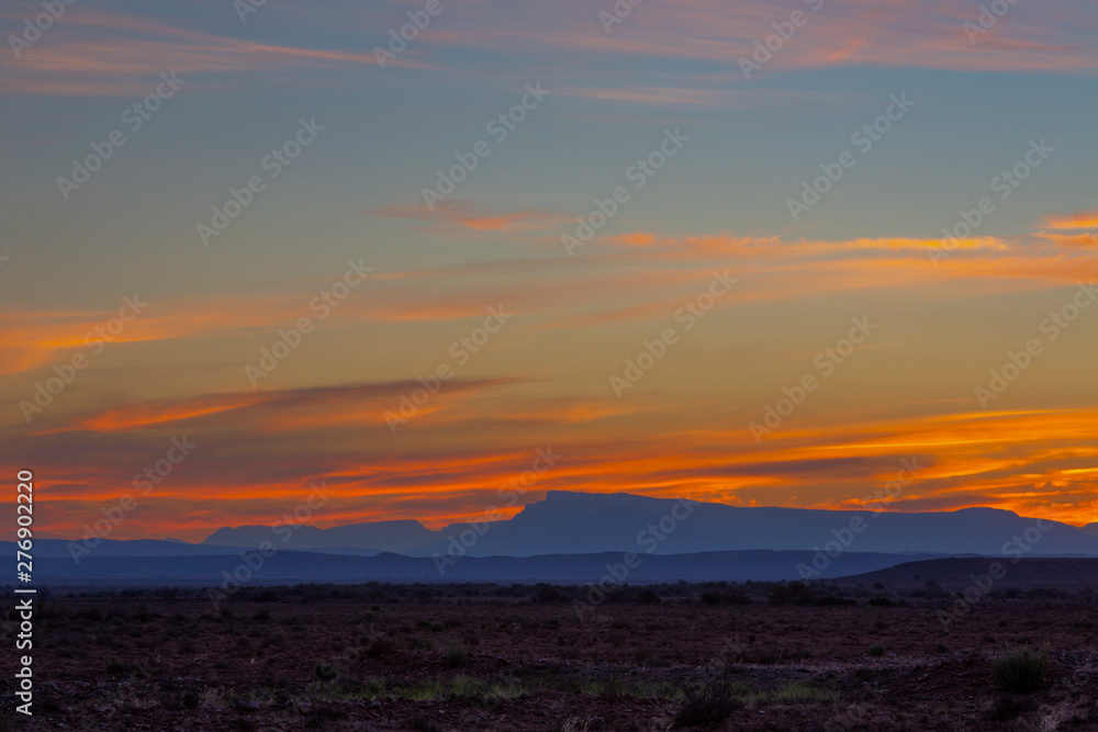 Sky colored yellow and orange above blue mountains on the horizon