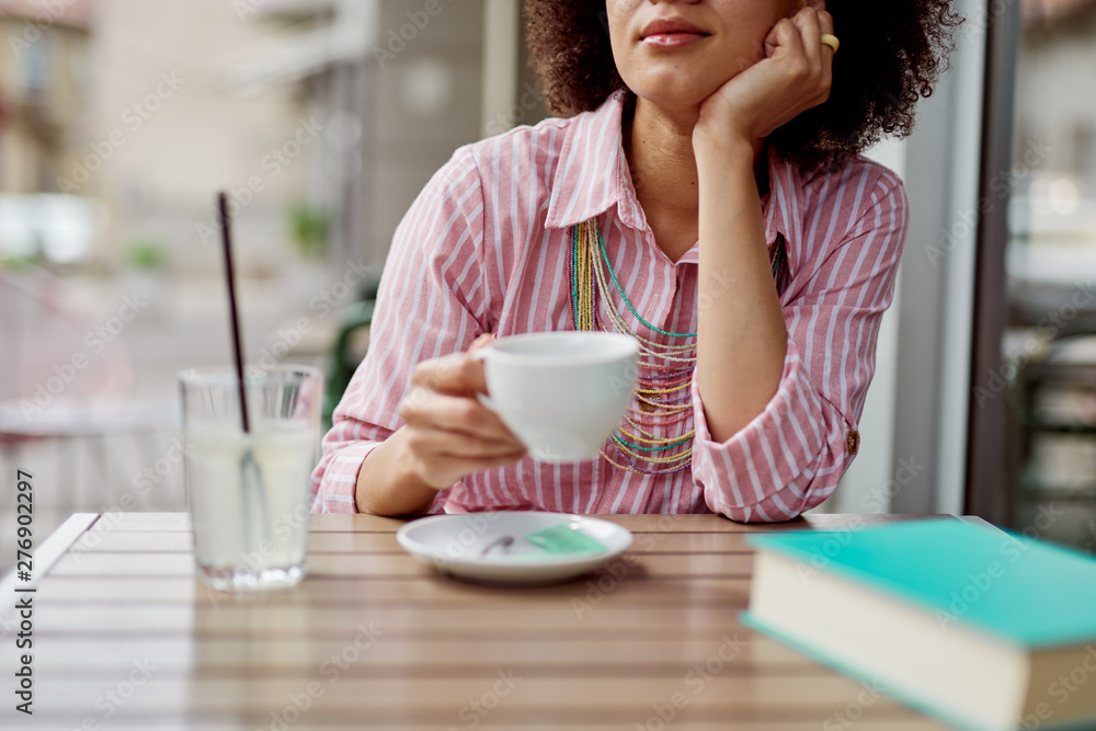 Attractive mixed race woman sitting in cafe and enjoying her coffee. Attractive mixed race woman sitting in cafe and enjoying her coffee.