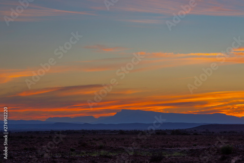 Sky colored yellow and orange above blue mountains on the horizon