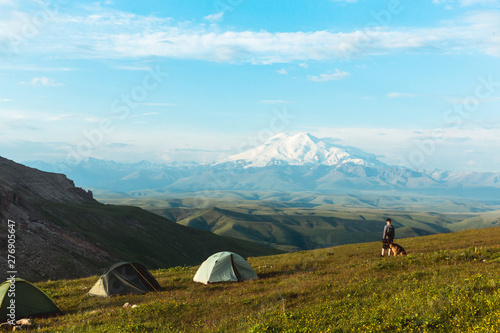 Man with dog Camping tent in Mountains Caucasus Elbrus Landscape Travel Lifestyle concept adventure vacations outdoor hiking gear equipment