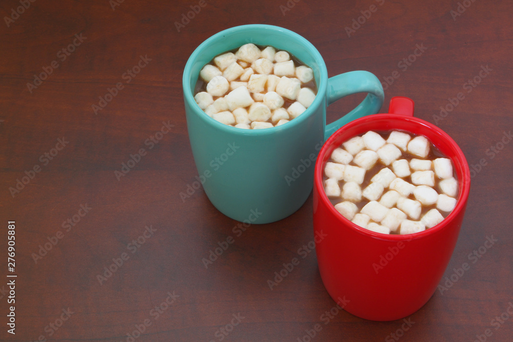 Red and blue cups with cocoa drink and marshmallows on wooden table with room for text Red and blue cups with cocoa drink and marshmallows on wooden table with room for text