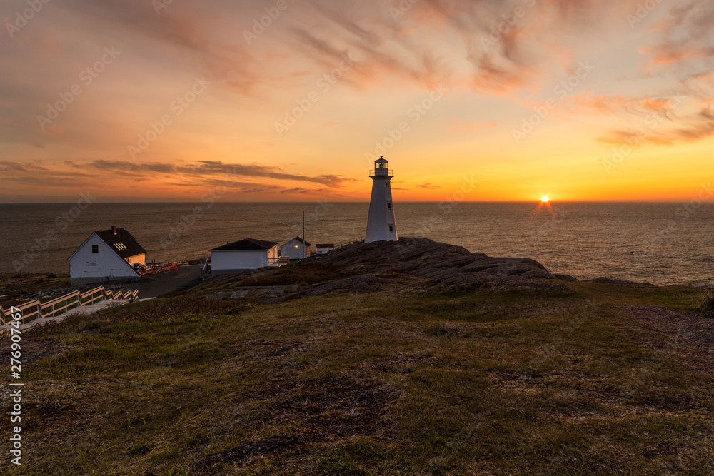 Beautiful sunrise over a white lighthouse sitting at the edge of a rocky cliff. Cape Spear National Historic Site, St Johns Newfoundland. 