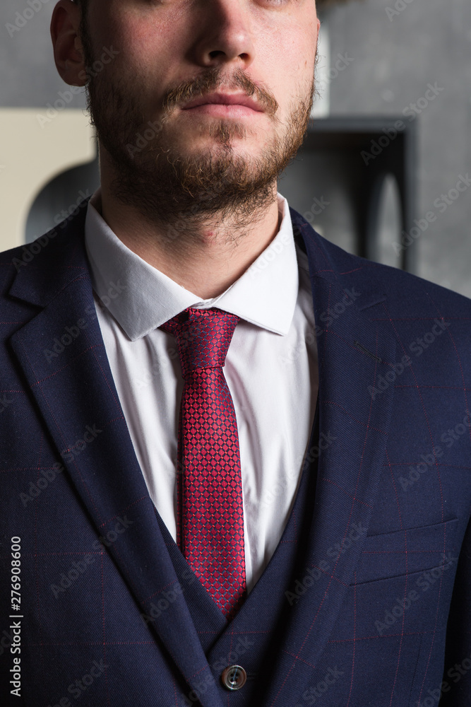 Close up portrait of an elegant man in a three-piece suit stands in interior studio Close up portrait of an elegant man in a three-piece suit stands in interior studio