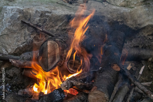 yellow red camp fire in the woods with big rock