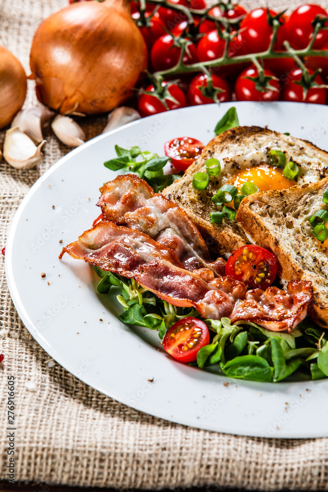 Breakfast - toasted bread with fried egg, bacon and vegetables Breakfast - toasted bread with fried egg, bacon and vegetables