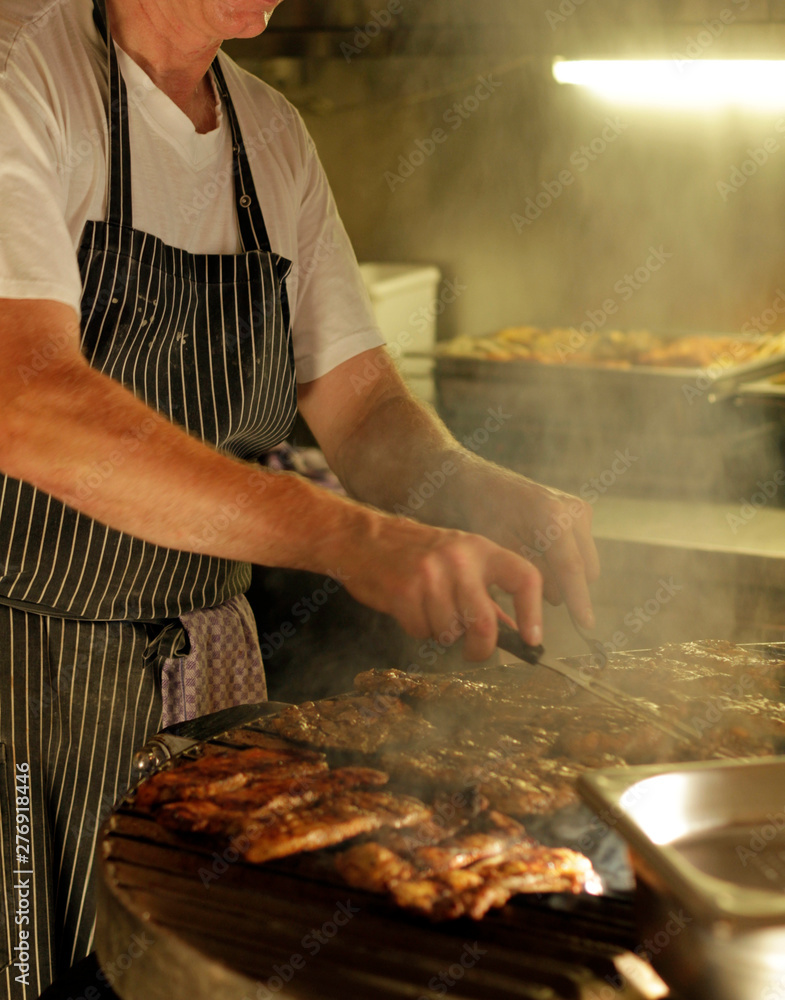 Man wearing an apron working the bbq grill Man wearing an apron working the bbq grill
