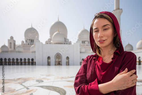 Woman at Abu Dhabi Mosque. Wearing a red Hijab looking at the Sheikh Zayed Grand Mosque in UAE. Sunny day, beautiful architecture views photo