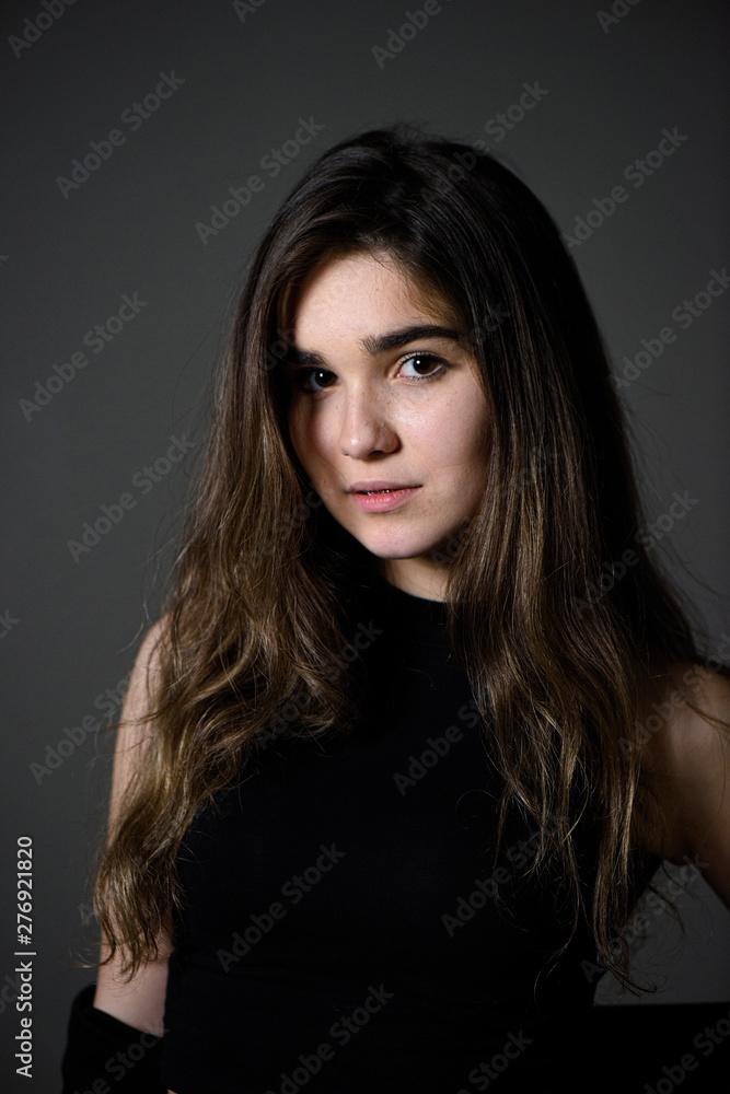 Young caucasian girl with brown hair posing on grey background Young caucasian girl with brown hair posing on grey background