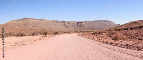 Gravel dirt road leading towards mountains in Central Namibia