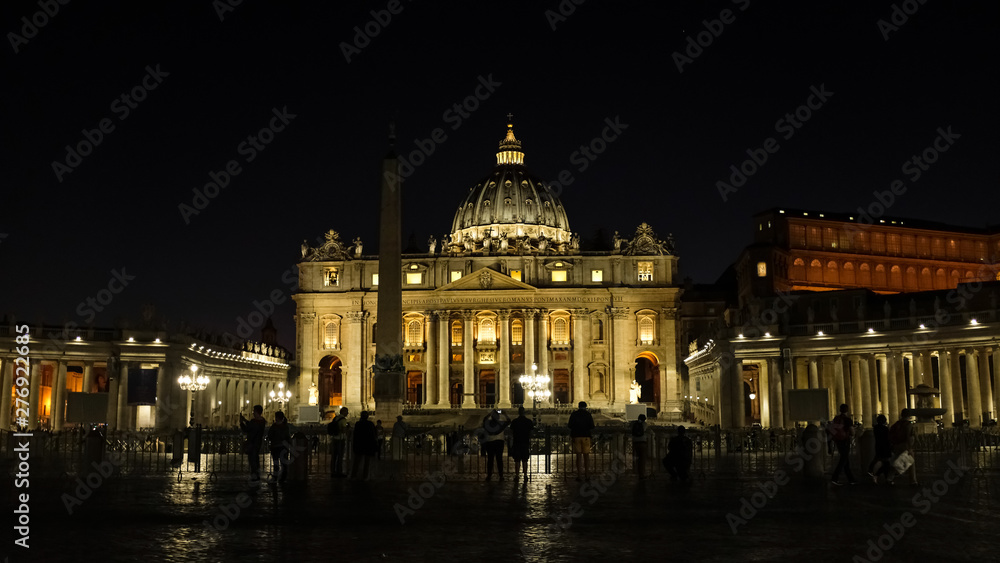 Illuminated Saint Peter cathedral by night, with people tourists taking pictures and star on sky,rome italy 