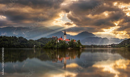 Bled, Slovenia - Beautiful golden sunrise at Lake Bled (Blejsko Jezero) with the Pilgrimage Church of the Assumption of Maria on a small island and Bled Castle and Julian Alps at background