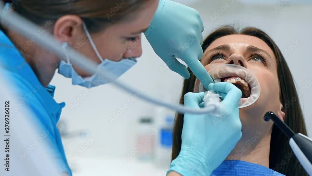 Dentist And Assistant Perform Installation Procedure Of Bracket. Close Up Dentist And Assistant Perform Installation Procedure Of Bracket. Close Up