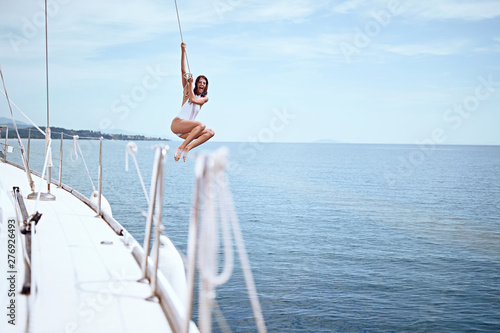 Girl jumping from sailing boat in sea. .