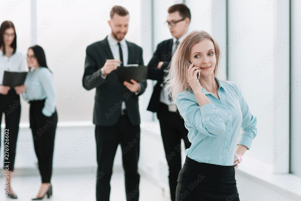 young business woman talking on a smartphone standing in the office hallway. young business woman talking on a smartphone standing in the office hallway.