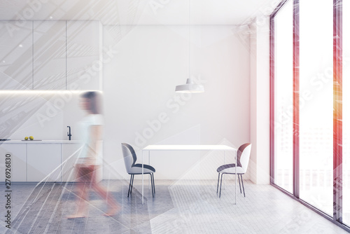 Woman walking in white kitchen with table