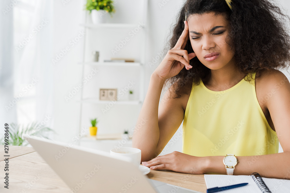 selective focus of tired curly brunette african american woman with closed eyes having headache selective focus of tired curly brunette african american woman with closed eyes having headache