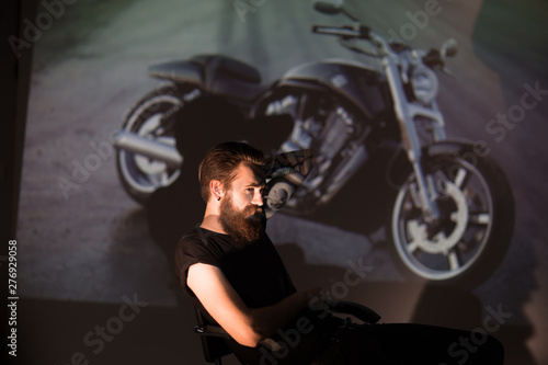 serious stylish biker man looking through the slides of his motorcycle