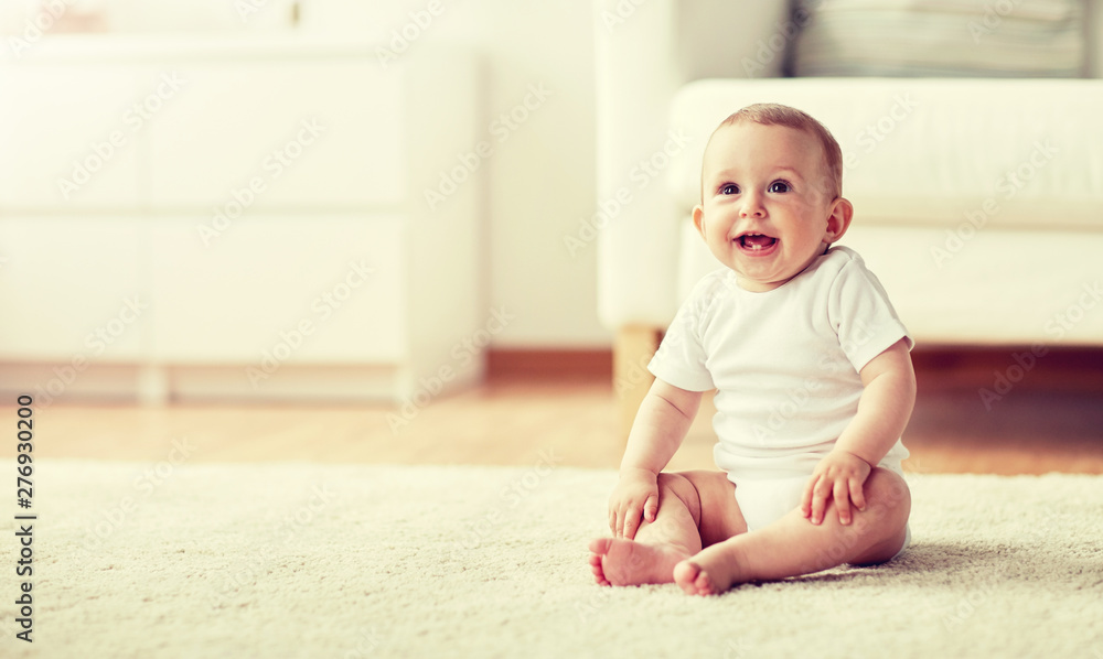 childhood, babyhood and people concept - happy little baby boy or girl sitting on floor at home childhood, babyhood and people concept - happy little baby boy or girl sitting on floor at home