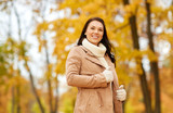 season, fashion and people concept - happy young woman smiling in autumn park