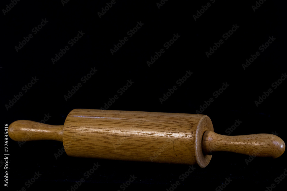 Wooden rolling pin on black background Wooden rolling pin on black background