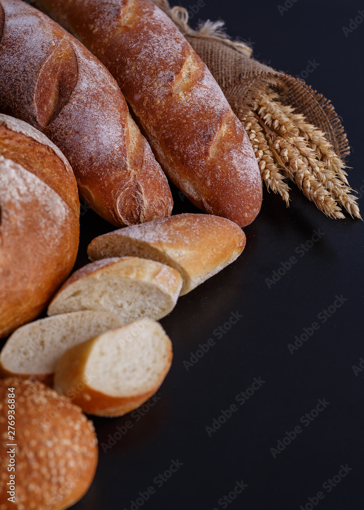 Bakery - gold rustic crusty loaves of bread and buns on black chalkboard background.