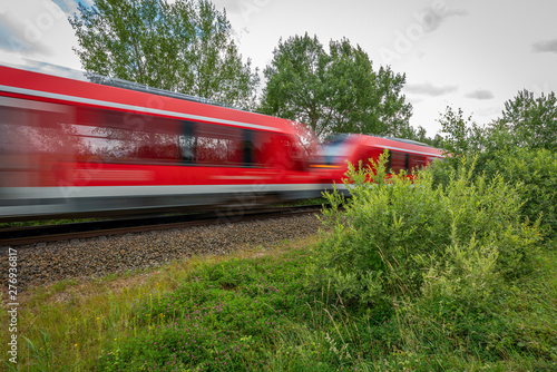 a red train races past a camera