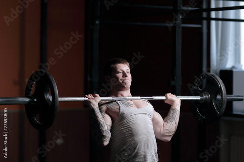 male bodybuilder doing exercises with a barbell