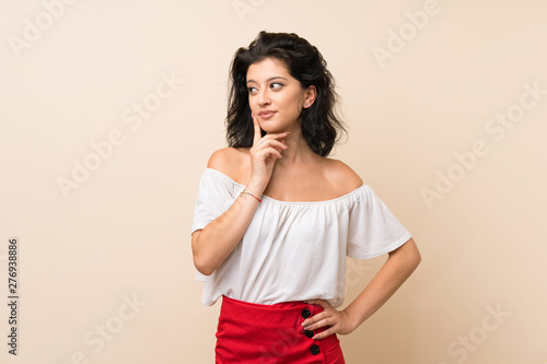 Young woman over isolated background thinking an idea while looking up