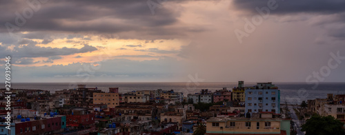 Aerial Panoramic view of the residential neighborhood in the Havana City, Capital of Cuba, during a colorful  and rainy sunset. © edb3_16