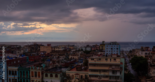 Aerial Panoramic view of the residential neighborhood in the Havana City, Capital of Cuba, during a colorful  and rainy sunset. © edb3_16