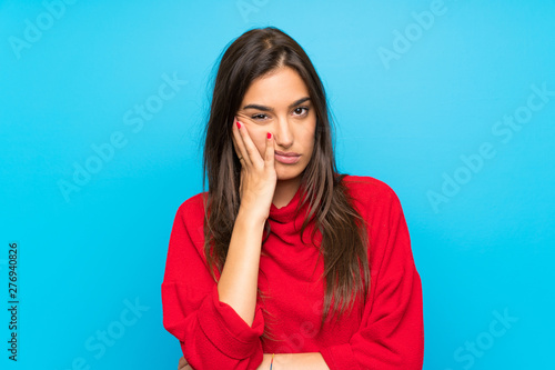 Obraz na plátně Young woman with red sweater over isolated blue background unhappy and frustrate