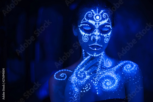 Foto Body art on the body and hand of a girl glowing in the ultraviolet light