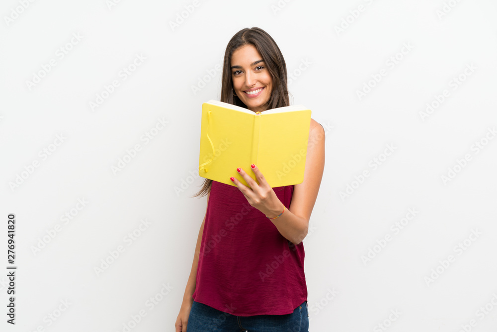 Young woman over isolated white background holding and reading a book Young woman over isolated white background holding and reading a book