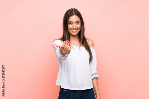 Young woman over isolated pink background inviting to come with hand. Happy that you came