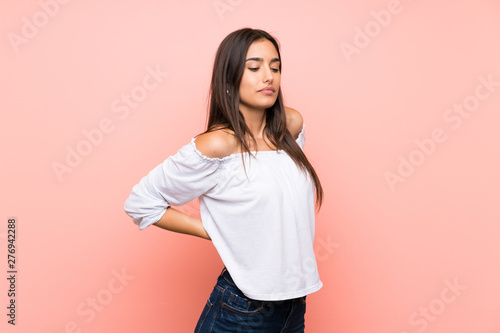 Young woman over isolated pink background suffering from backache for having made an effort