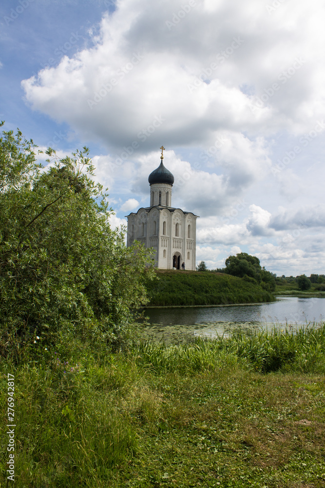 White stone Church of the Intercession on the Nerl with reflection in the water summer day Russia