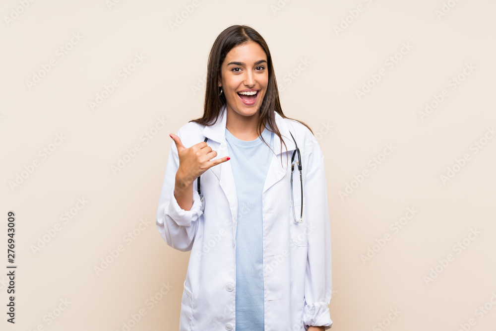 Young doctor woman over isolated background making phone gesture