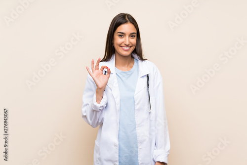 Young doctor woman over isolated background showing an ok sign with fingers