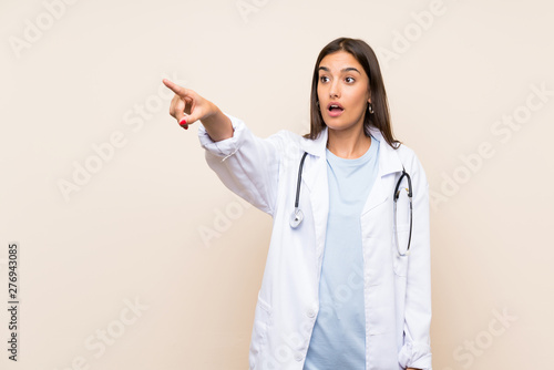 Young doctor woman over isolated background pointing away