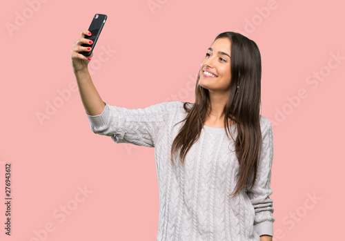 Young hispanic brunette woman making a selfie over isolated background