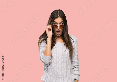 Young hispanic brunette woman with glasses and surprised over isolated background © luismolinero