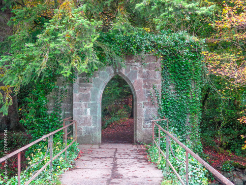 Photo Overgrown archway at the end of a bridge