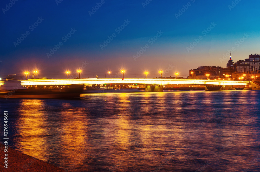 White nights in Saint-Petersburg. Tourism in Russia. Northern night in midsummer. Beautiful twilight glow and glitter. A bridge with lights reflected in the Neva river. Welcome to St. Petersburg.