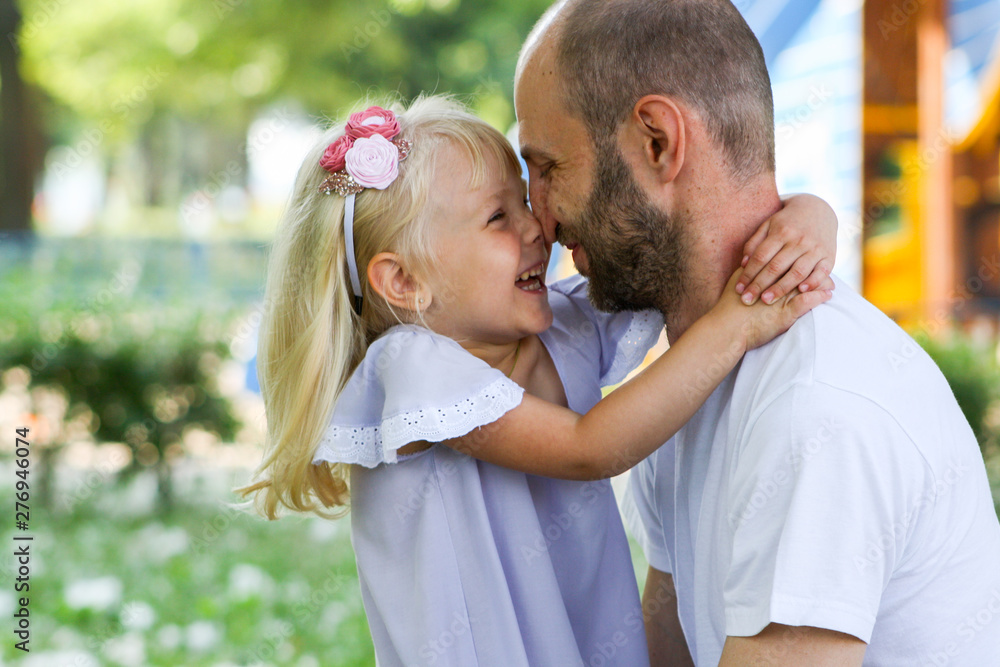 Happy father and daughter spending time together in a park on a summer day and warmly hugging each other. Happy father and daughter spending time together in a park on a summer day and warmly hugging each other.