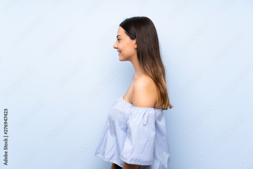Young brunette woman over isolated blue background looking to the side Young brunette woman over isolated blue background looking to the side