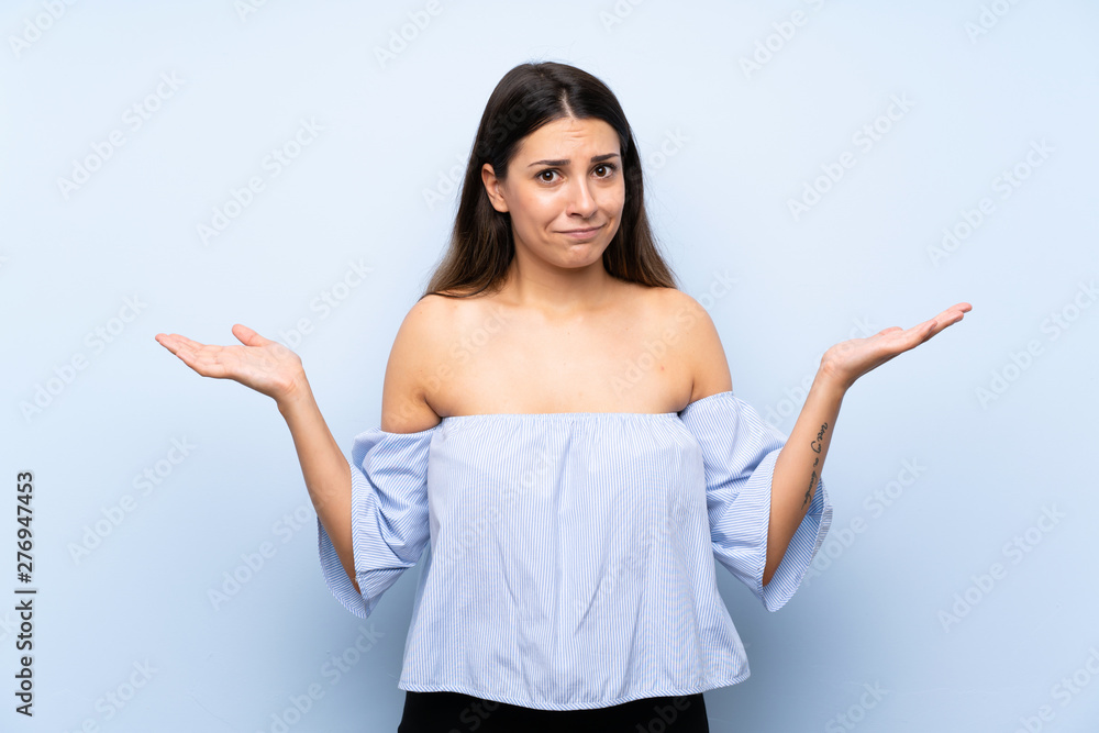 Young brunette woman over isolated blue background having doubts with confuse face expression Young brunette woman over isolated blue background having doubts with confuse face expression