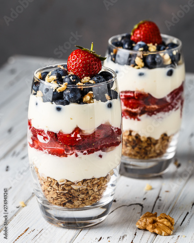 Two pieces of puff glass dessert with granola, mascarpone cream, strawberry, blueberry and walnuts