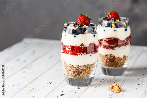 Two pieces of puff glass dessert with granola, mascarpone cream, strawberry, blueberry and walnuts