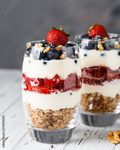 Two pieces of puff glass dessert with granola, mascarpone cream, strawberry, blueberry and walnuts