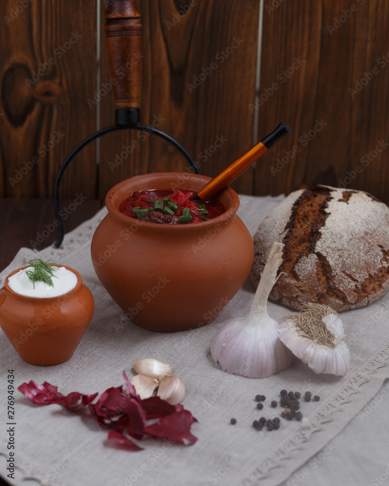 Rustic still life with borsch in a clay pot, green onions and bread Rustic still life with borsch in a clay pot, green onions and bread